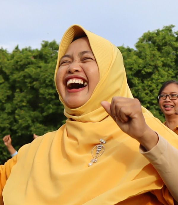 Group of excited people in Indonesia, including those living with disabilities, outdoors, pumping their fists in the air. Credit: INKLUSI