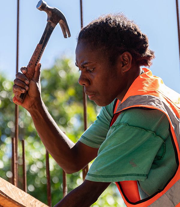 A construction worker with hammer in hand on a building site in Vanuatu. Credit: DFAT