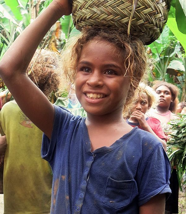 A young girl in the Solomon Islands carries a basket on her head filled with food. Credit: DFAT